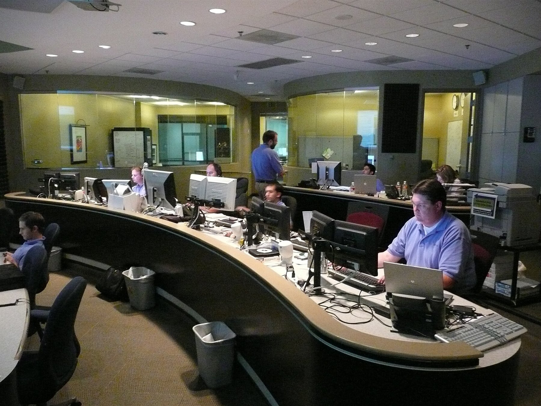 Network operations center with monitoring screens and workstations, representing governed agentic workflows.